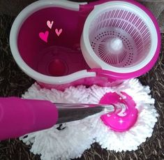 a pink and white mop is laying on the floor next to it's holder