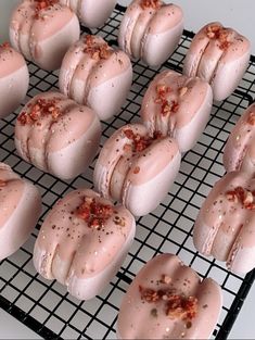 several donuts with pink icing and sprinkles on a cooling rack