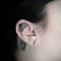 a woman with a spider web tattoo on her ear