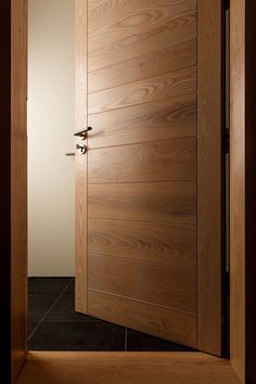 an open wooden door in a room with tile flooring and wood paneling on the walls