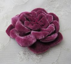 a close up of a flower on a white cloth material with some lace in the background