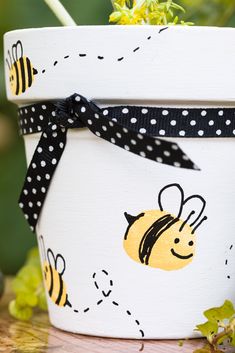 a white pot with black polka dots and a bee painted on it