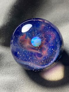 a blue glass object sitting on top of a gray surface with stars in the sky