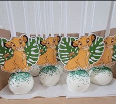 the lion king cake pops are decorated with green sprinkles and white frosting