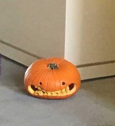 an orange pumpkin sitting on the floor with its mouth open