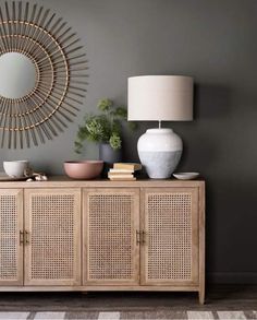 a living room with a large mirror and wicker sideboard