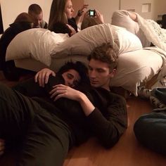 two people are laying on the floor with their arms around each other and one person is taking a selfie