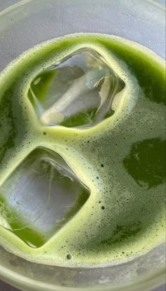 green liquid in a glass with ice cubes on the bottom and some water inside