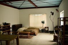 a bedroom with a bed, desk and speakers on the floor in front of a window