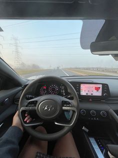 a person driving a car on a highway with the dashboard and steering wheel up close