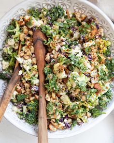 a white bowl filled with salad and two wooden spoons