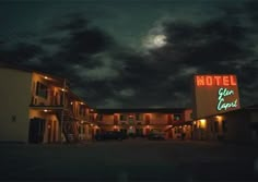 the motel is lit up at night and it's full moon in the sky