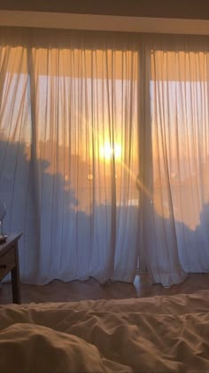 the sun is setting in front of some curtains