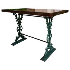 an old fashioned table with metal legs and wood top