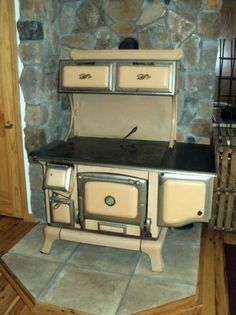 an old fashioned stove is in the corner of a room with wood floors and stone walls