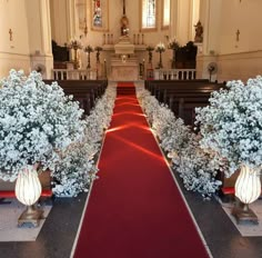 an empty church with red carpet and white flowers