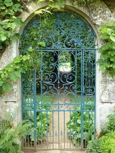 an iron gate is surrounded by vines and greenery in front of a stone wall