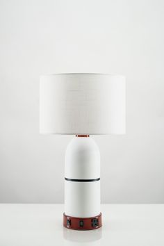 a white table lamp with a brown base and a white shade on it's top