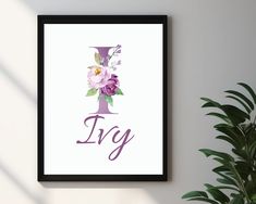 a framed poster with the letter ly and flowers on it next to a potted plant