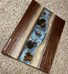 a wooden box filled with rocks and water on top of a carpeted floor next to a rug