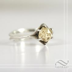 a gold and silver ring with a clock on it's side, sitting on a white surface