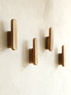 three wooden hooks mounted to the side of a wall