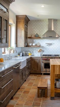 a kitchen with wooden cabinets and tile flooring, an island countertop and stainless steel appliances