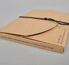 an open book with a string attached to it sitting on top of a cardboard box