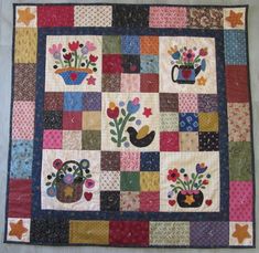 a patchwork quilt with flowers and potted plants on the front, in multi - colored squares