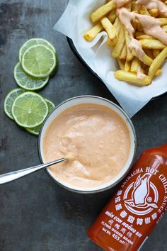 there is a bottle of ketchup next to some fries and limes on the table