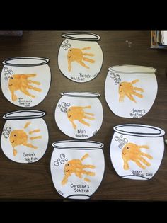 six handprints on white paper with orange and black cats in the bowl, one is