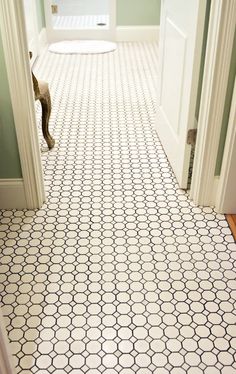 an open door leading to a bathroom with white and black tiles on the floor,