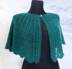 a green crocheted shawl on a mannequin