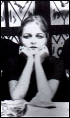 a woman sitting at a table with her hands on her face and looking to the side