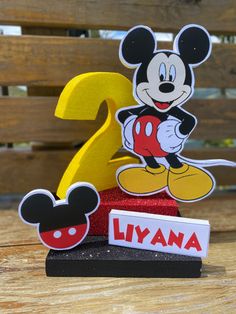 the number two is placed next to a mickey mouse figurine on a wooden table