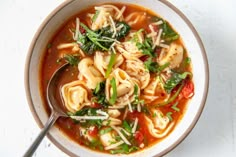 a white bowl filled with pasta and spinach soup