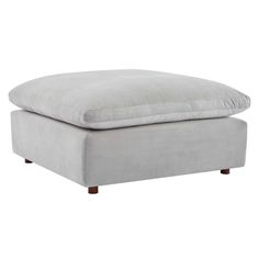 a grey ottoman with a pillow on the top and bottom part, in front of a white background