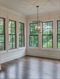 an empty room with three windows and wood floors