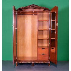 an antique wooden armoire with shelves and drawers in front of a green wall behind it