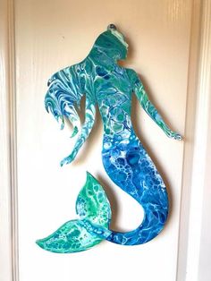 a blue and green mermaid statue hanging on the side of a door