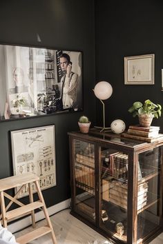 a living room with black walls and pictures on the wall, including an old bookcase