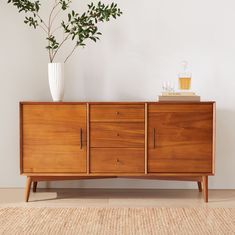 a wooden sideboard sitting on top of a hard wood floor next to a potted plant