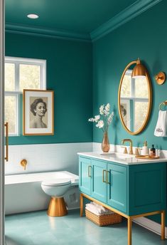 a bathroom with teal walls and gold accents on the sink, toilet, and bathtub