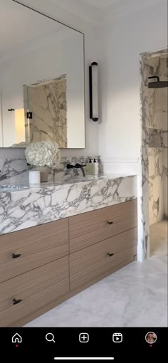 a bathroom with marble counter tops and white walls, along with large mirrors on the wall