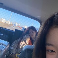 a woman sitting in the back seat of a car with her luggage on the floor