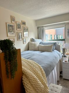 a bed sitting in a bedroom next to a window with pictures on the wall above it