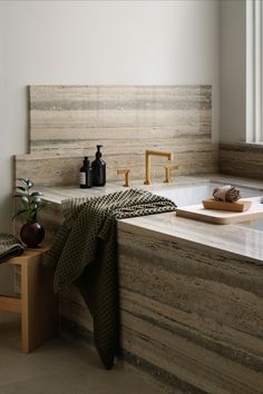 a bath tub sitting under a window next to a wooden counter top with towels on it