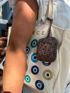 a woman carrying a crocheted bag with an eye patch on the front pocket