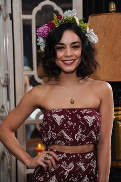 a woman wearing a flower crown standing next to a lamp