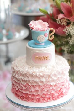 a three tiered cake with pink and blue frosting on top, sitting on a plate